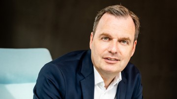 Jochen Schmitz sitzend in blauem Anzug
